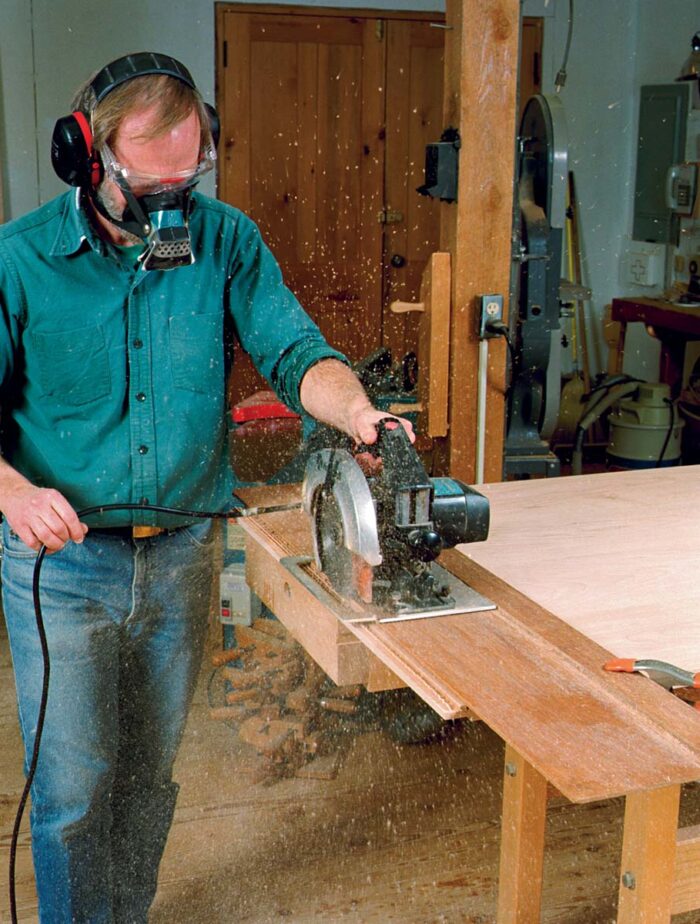 Using a saw guide made from two strips of in. plywood, the author roughs out the breadboard tenons by cutting a series of kerfs on both sides of the top.