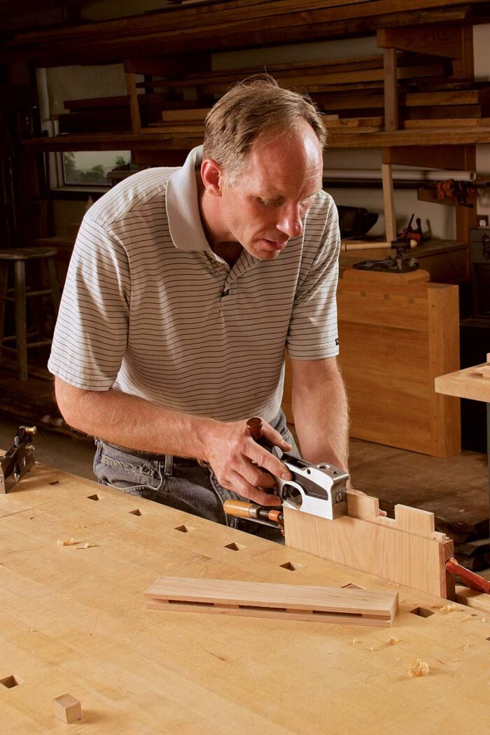 The jig’s built-in fence helps prevent tearout. Wider workpieces are mounted in a vise and cut without the aid of a bench hook