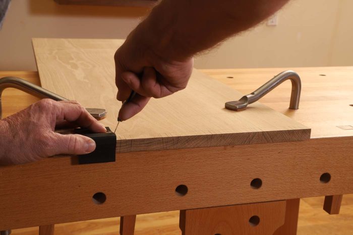 Now that the knife marks are scribed onto the end grain of the pin board, I lay the pin board down with the interior facing up and, using a square and marking knife, extend the end marks down to the baseline.