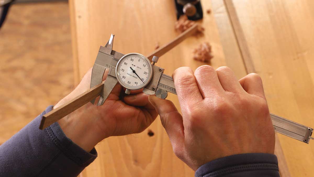 Unplugged planer. For accurate sizing of thin parts like splines, Korsak brings stock to rough thickness with a planer or bandsaw, then finishes with a block plane. He checks progress often with dial calipers. The plane is easily wielded with one hand, leaving his other hand free to pin the workpiece in place.