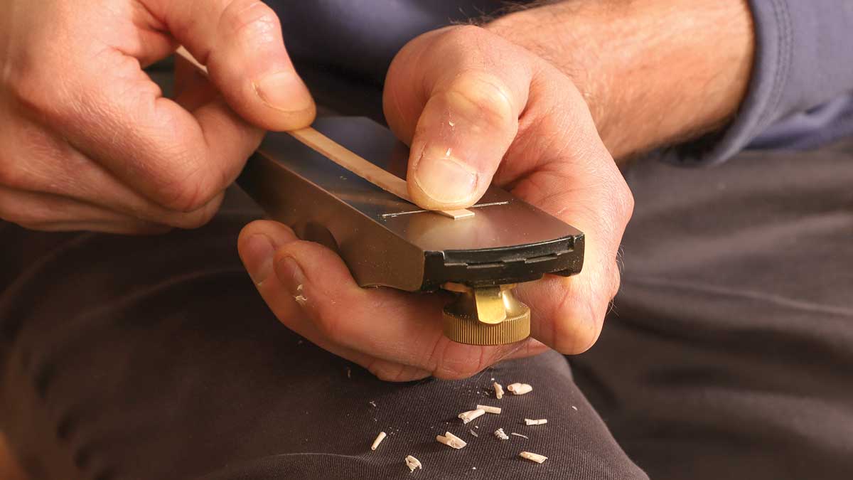 Wedge work. After cutting a strip 1⁄16 in. thick at the bandsaw, Korsak tapers one end of it by pulling it across the block plane’s blade in a series of lengthening cuts.