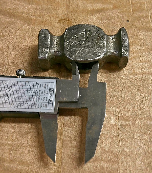 The process of measuring the eye of a hammer.