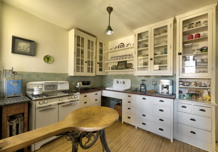 A remodeled kitchen in a Chicago flat originating in 1915, with white cabinetry and blue backsplash.