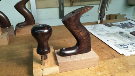 a set of wooden knobs and handles for a handplane on a workbench