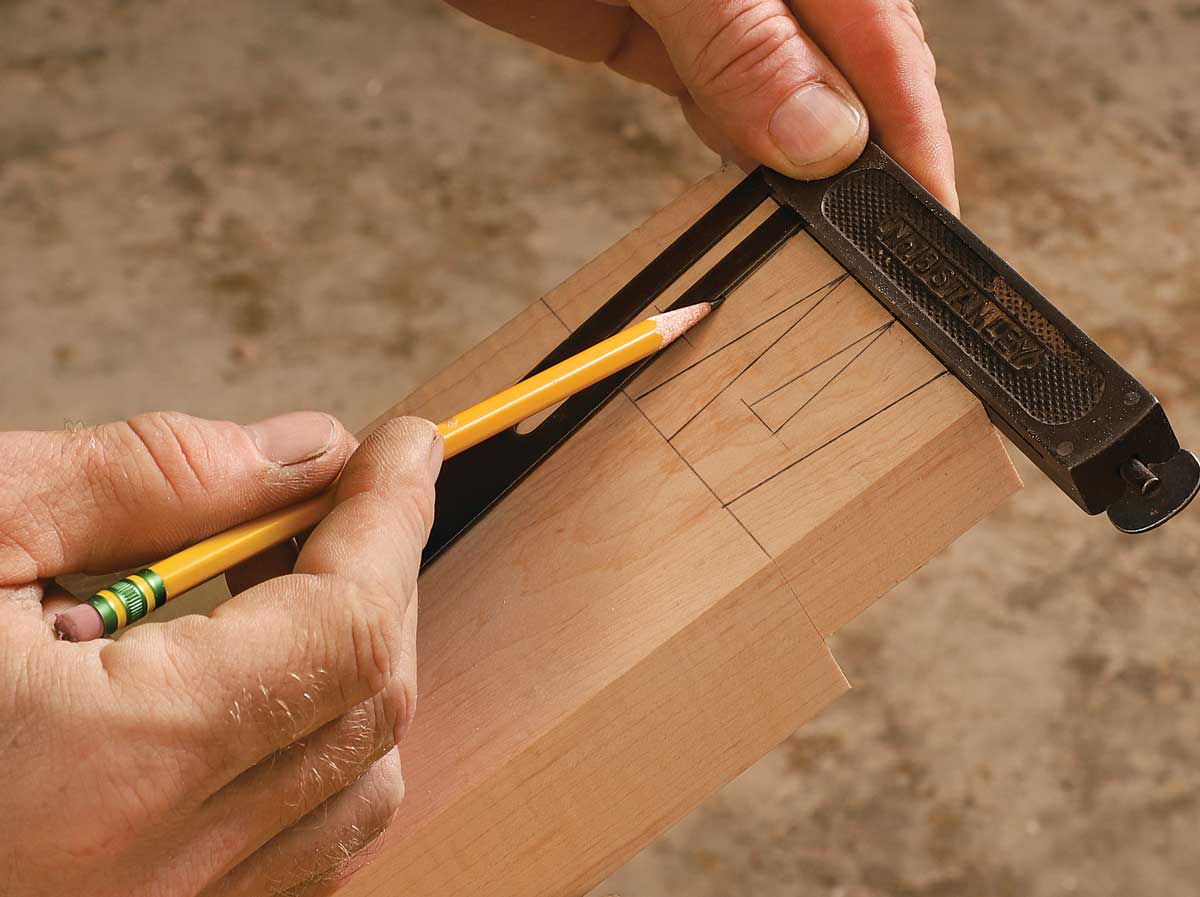 Lay down the angles. After drawing the crossgrain baseline lightly with a pencil, mark the dovetail angles for the tails and the pin sockets.