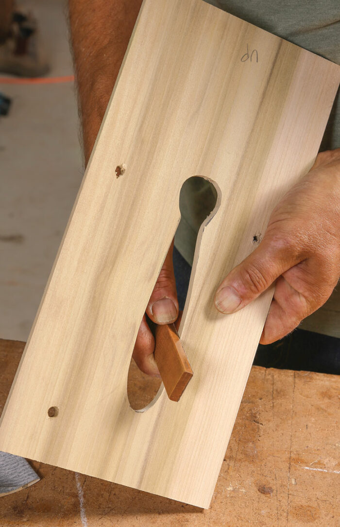 Scrollsaw and smooth. At the scrollsaw, carefully cut the shape out. Then smooth it with sandpaper. Newell glues sandpaper to a small scrap for more control.