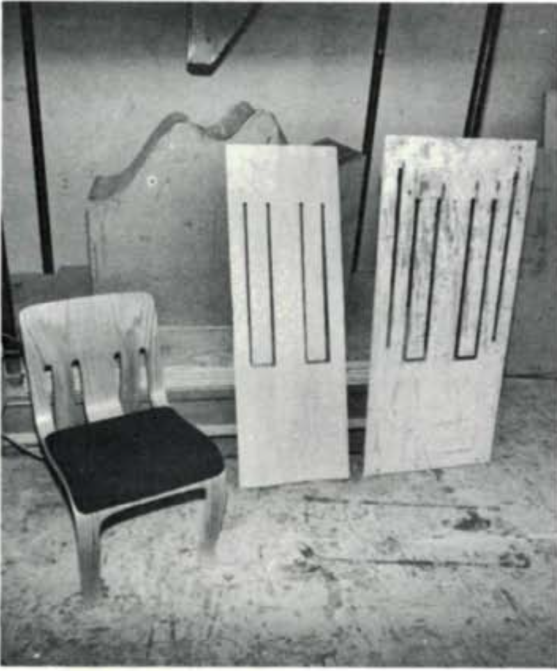 A bent laminated chair next to two sheets of plywood with recesses cut out that will form the chair. 