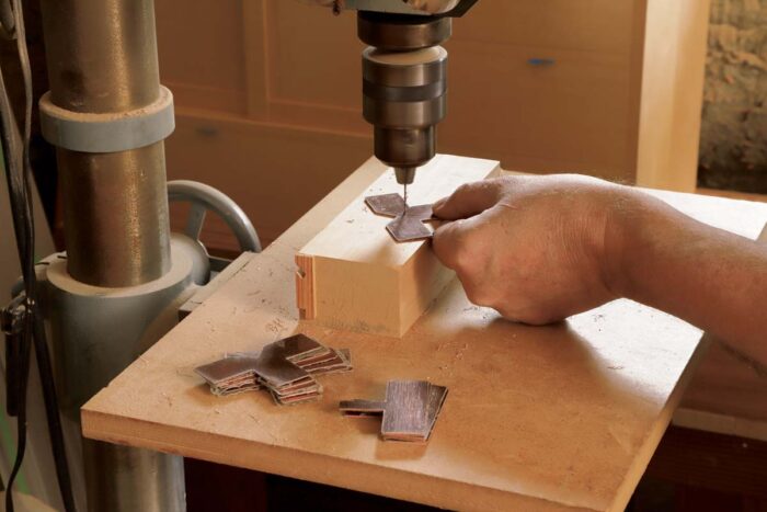 A piece of copper is being drilled at the drill press.