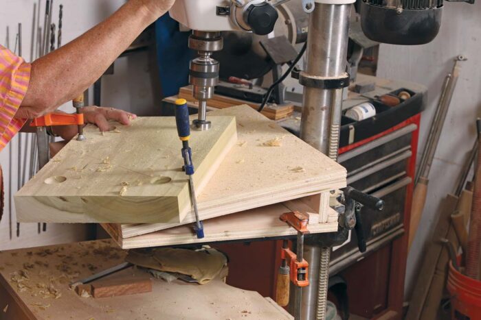 Beth uses a forstner bit to drill angled holes in the seat of a stool.