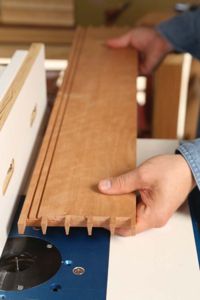 A board sits on the router table ready to have a groove routed into it.