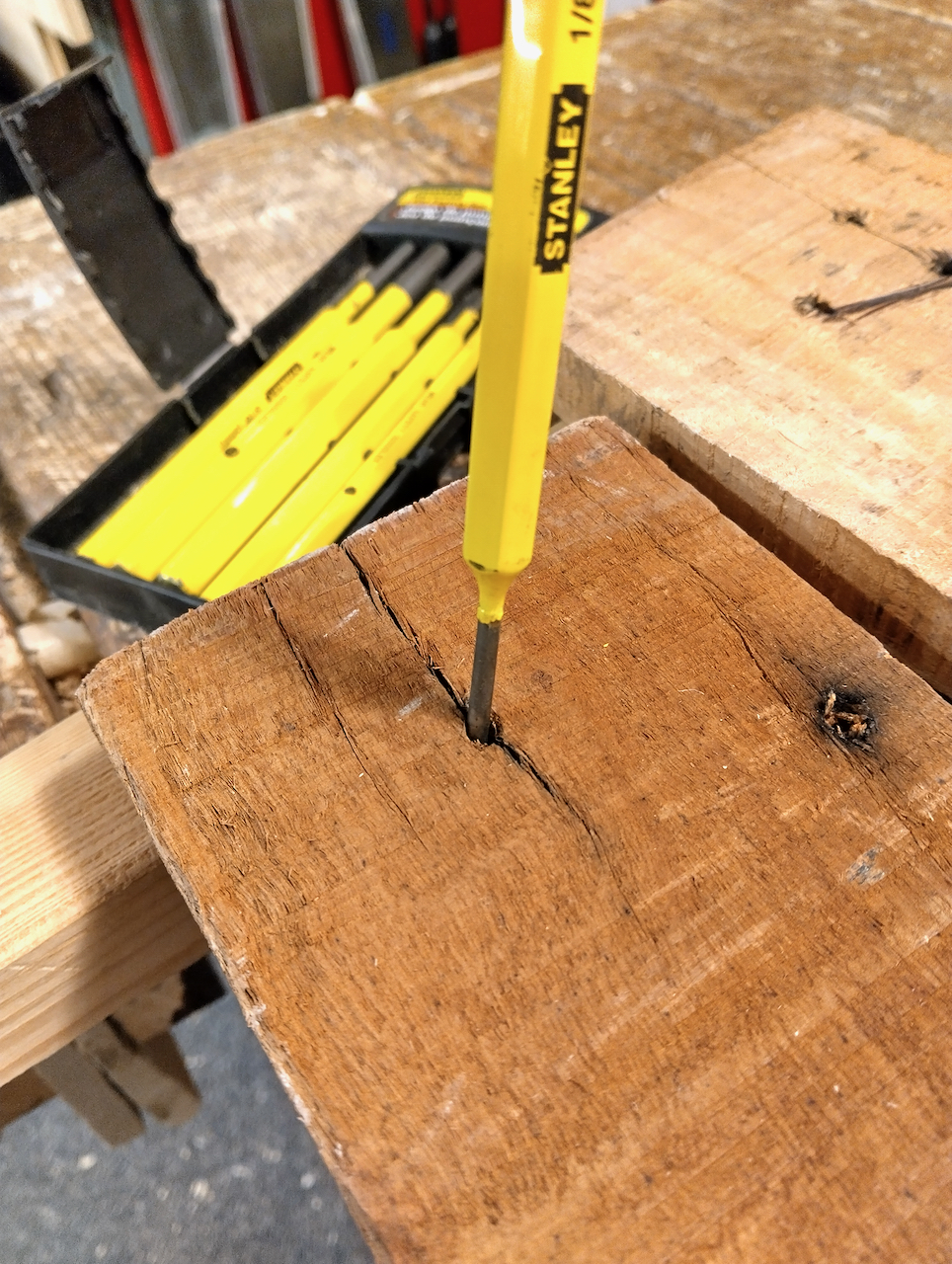 Yoav uses a nail punch to push the broken nail through the reclaimed board. 