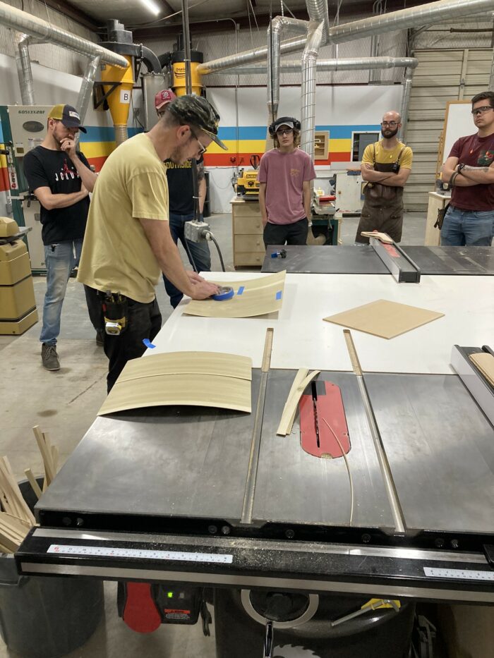 Philip Morley, the lead intructor at Austin School of Furniture, shows students how to seam veneer to create lumber core panels. 