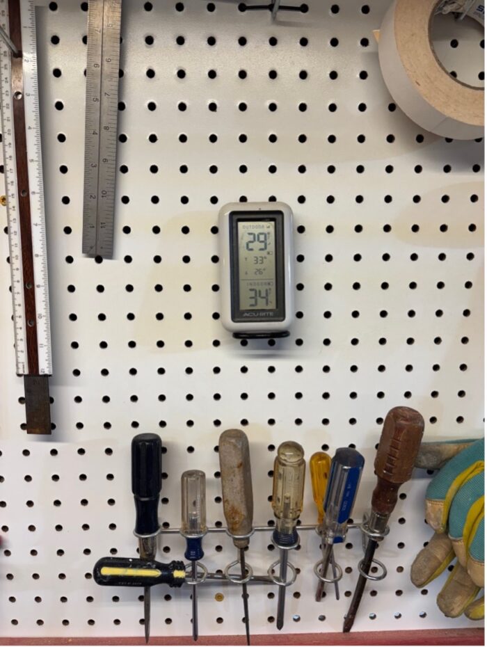 A digital thermometer hanging on a shop wall, showing 34 degrees Fahrenheit. 